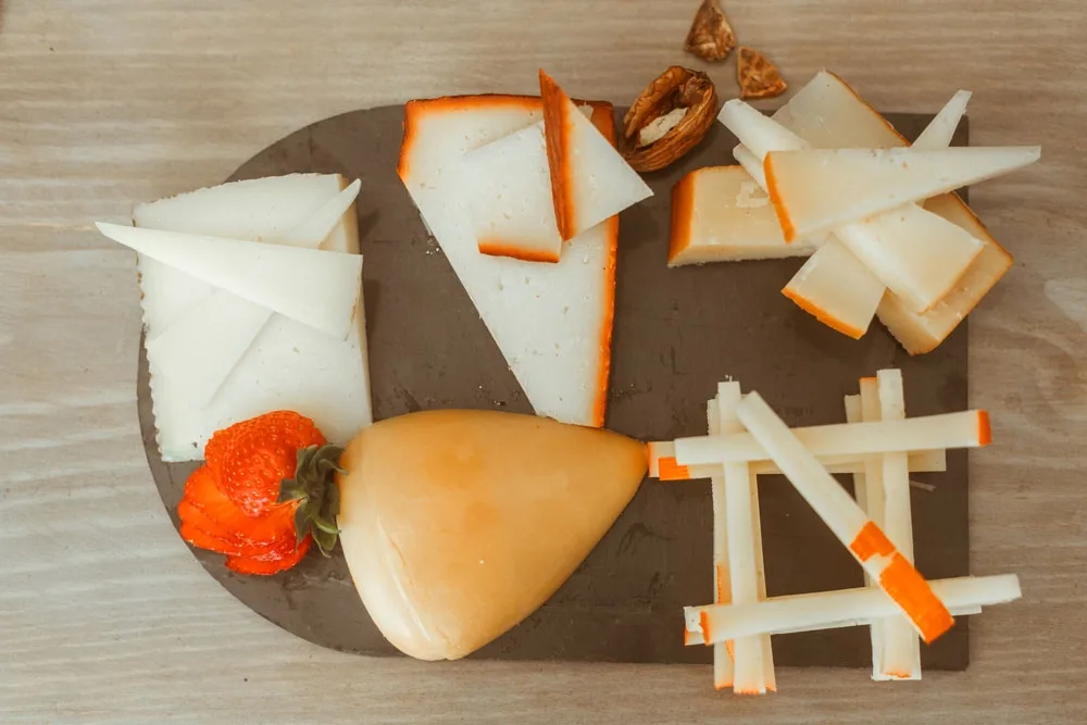 Tabla de quesos variados cortados en cuñas sobre pizarra